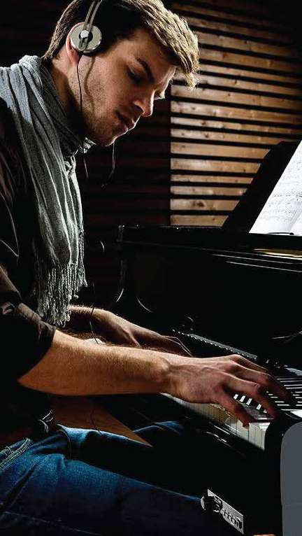 Pianista estudando com fones de ouvido em piano acústico com sistema Silent